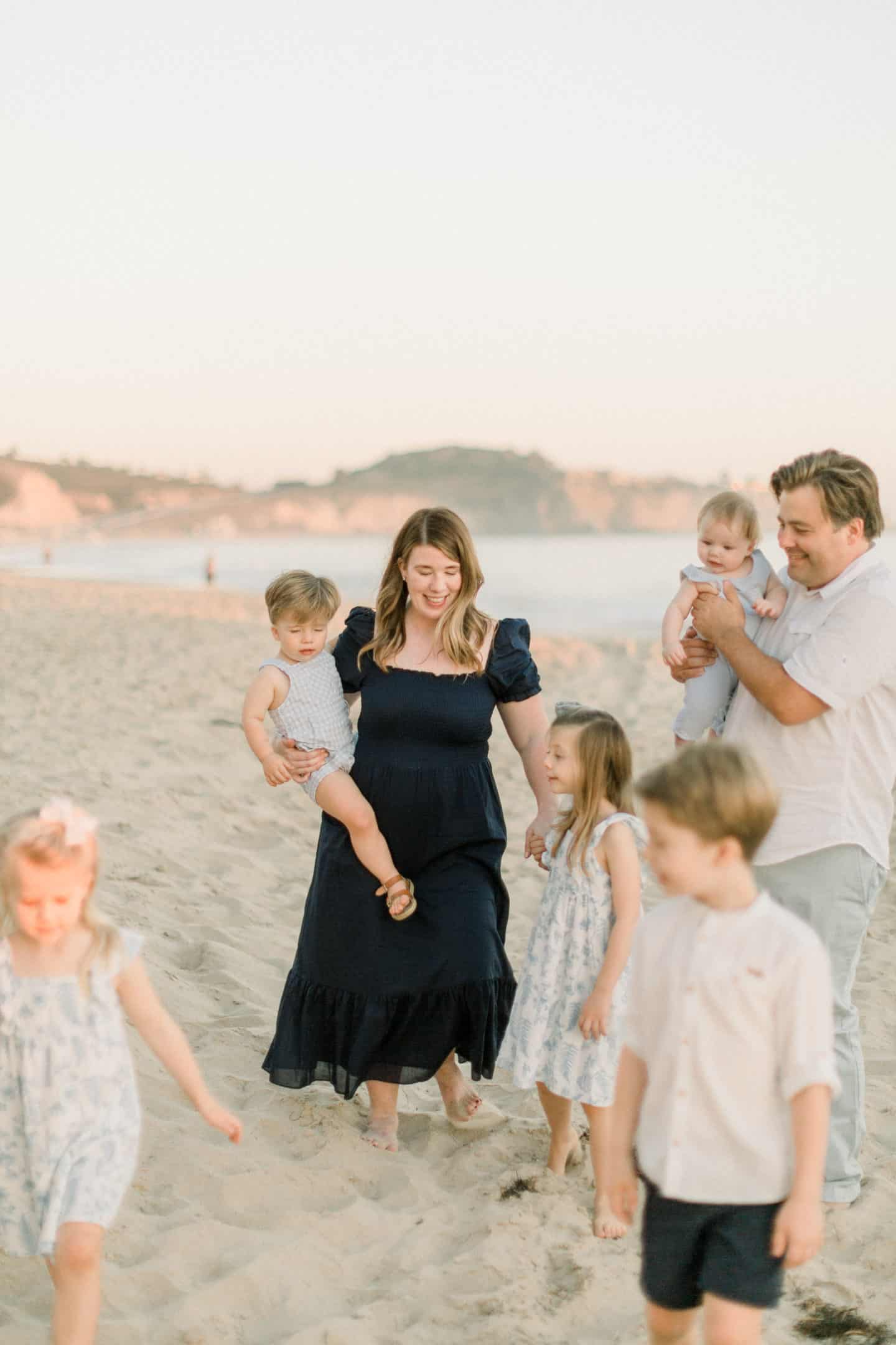 family of seven walking on the beach at sunset