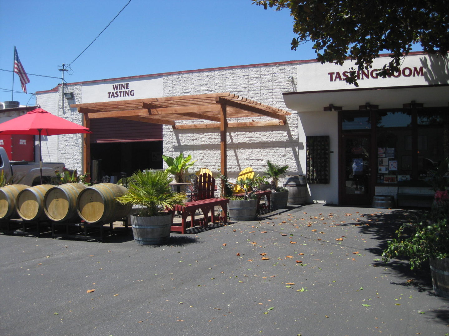 patio outside of wine tasting room. red umbrellas, wine barrels, and string lights